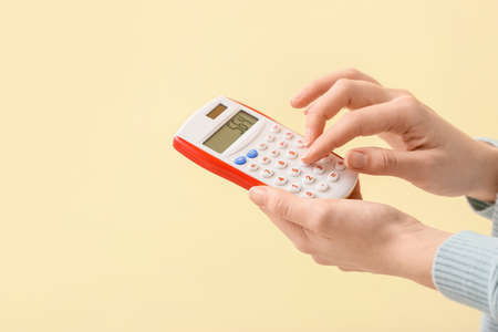 Female hands with calculator on color background