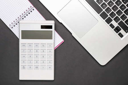 Modern calculator, notebook and laptop on dark backgroundの写真素材
