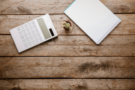 Modern calculator and notebook on wooden backgroundの写真素材