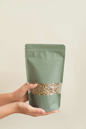 Hands with coffee bag on light background