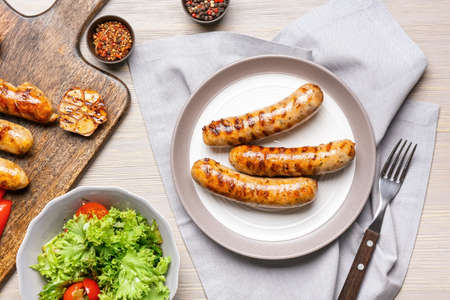 Plate with delicious grilled sausages and vegetables on tableの写真素材