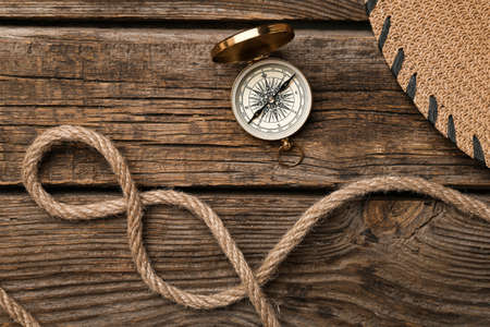 Rope and vintage compass on wooden background