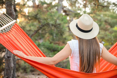 Beautiful young woman relaxing in hammock outdoorsの写真素材