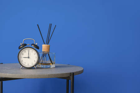 Stylish table with reed diffuser and clock near color wallの写真素材