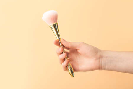 Hand with makeup brush on color background