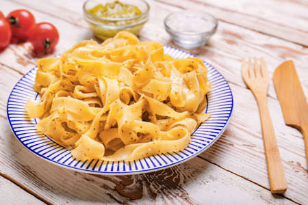 Plate with tasty pasta, pesto sauce and ingredients on wooden backgroundの写真素材
