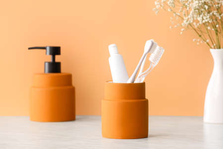 Holder with toothbrushes and toothpaste on table in bathroomの写真素材