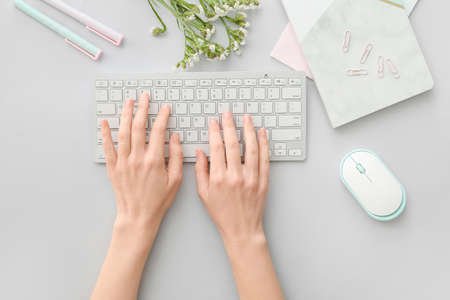 Female hands with computer keyboard, mouse and stationery on light backgroundの写真素材