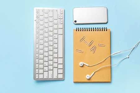 Computer keyboard, gadgets and stationery on color background