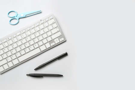 Computer keyboard, pens and scissors on white backgroundの写真素材