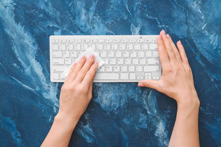 Woman cleaning computer keyboard on color backgroundの写真素材