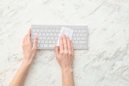 Woman cleaning computer keyboard on light backgroundの写真素材