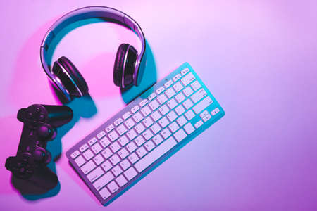 Computer keyboard, gamepad and headphones on color backgroundの写真素材
