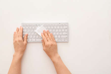Woman cleaning computer keyboard on white backgroundの写真素材