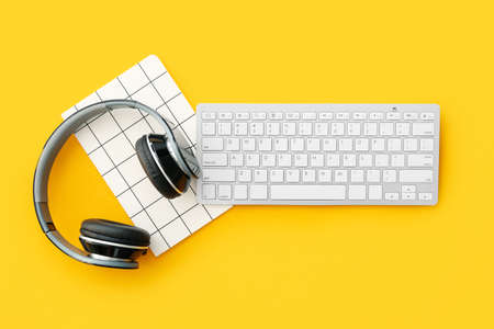 Computer keyboard, notebook and headphones on color backgroundの写真素材