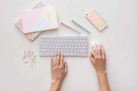 Female hands with computer keyboard, stationery and mobile phone on white backgroundの写真素材