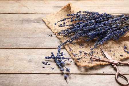 Beautiful lavender flowers and scissors on wooden background