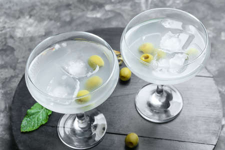 Glasses of tasty martini with olives on grunge background