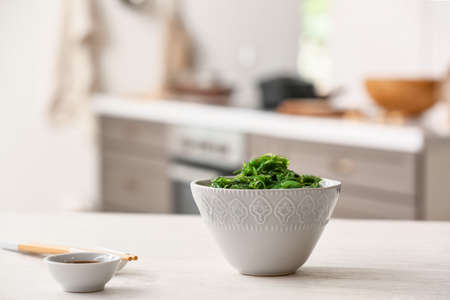 Bowl with tasty seaweed salad in kitchen