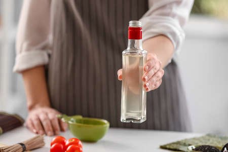 Woman with bottle of rice vinegar in kitchenの写真素材