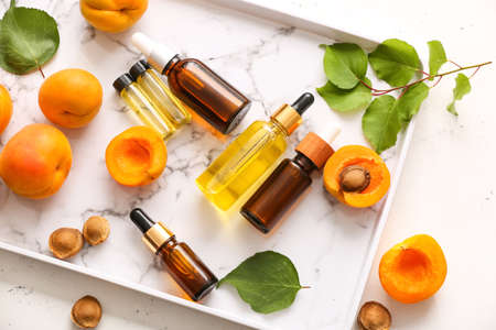 Bottles of apricot essential oil on trayの写真素材