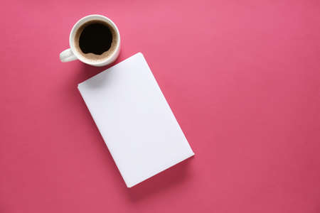 Blank book and cup of coffee on color backgroundの写真素材