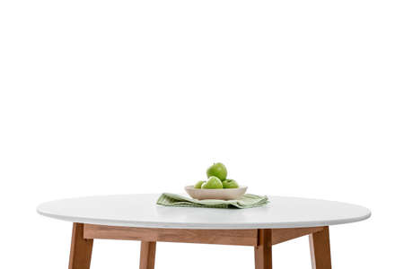 Plate with apples on table against white background