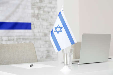 Glass with water and flag of Israel on table in embassy officeの写真素材
