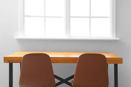 Table and chairs near wall with windowの写真素材