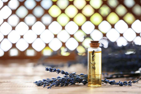 Bottle with lavender essential oil on wooden tableの写真素材