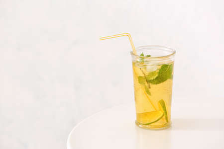 Glass of tasty cold ice tea on table against white background
