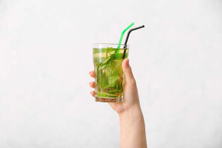 Female hand with glass of tasty cold tea on white backgroundの写真素材