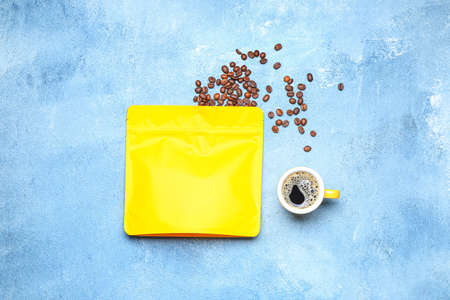 Blank coffee bag and cup on color background