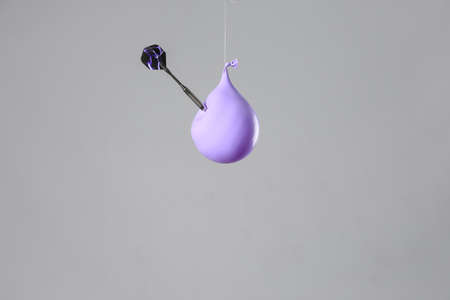 Throwing of dart in balloon with water on gray backgroundの写真素材