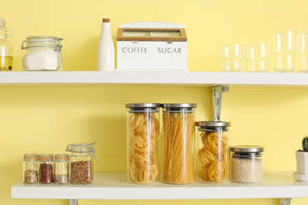 Set of utensils and glass jars with products on kitchen shelves
