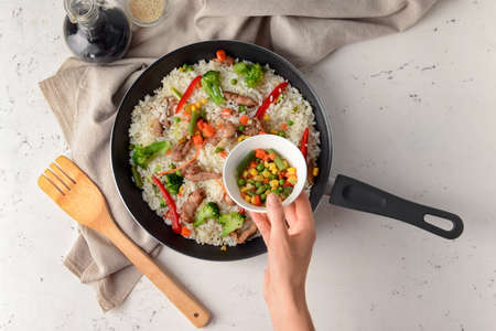 Woman cooking tasty fried rice, top viewの写真素材