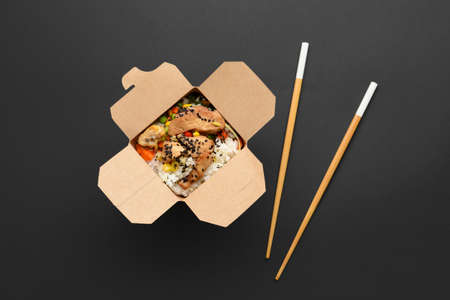 Box with tasty fried rice on dark background