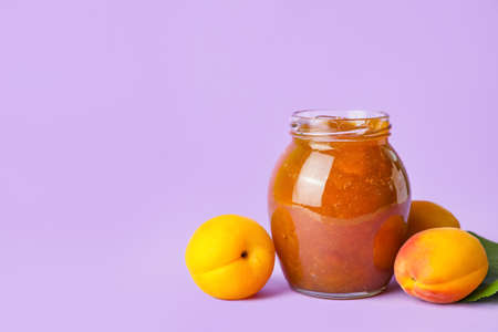 Jar of tasty apricot jam on color backgroundの写真素材