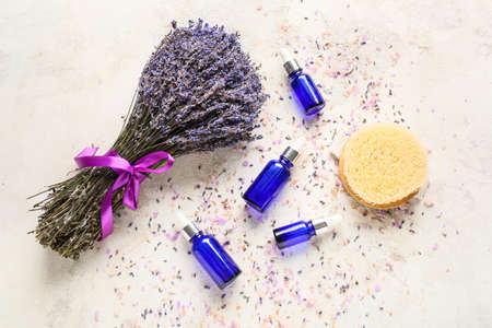 Lavender bouquet and bottles with essential oil on light backgroundの写真素材