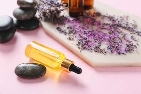Composition with essential oil bottles and lavender twigs on color backgroundの写真素材