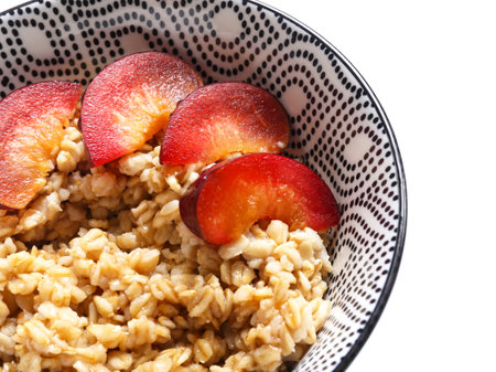 Bowl with tasty sweet oatmeal on white backgroundの写真素材