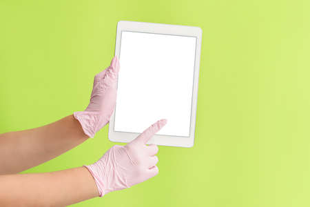Hands of doctor with tablet computer on color background