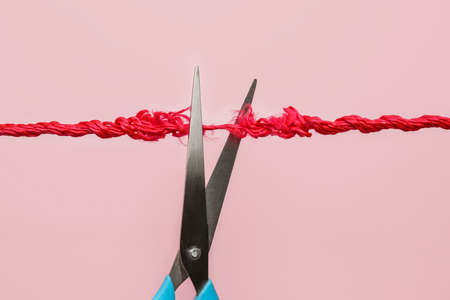 Scissors with frayed rope on color backgroundの写真素材
