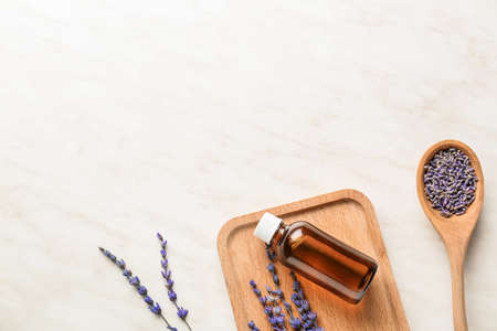 Lavender twigs and bottle with essential oil on light backgroundの写真素材