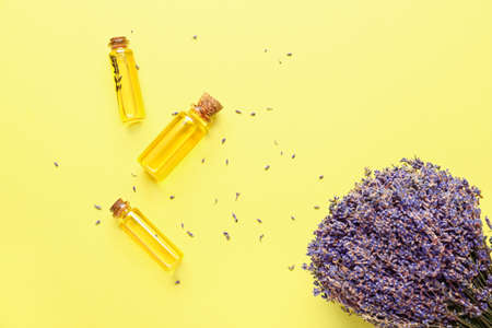 Lavender bouquet and bottles with essential oil on color backgroundの写真素材