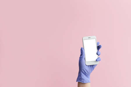 Hand of doctor with mobile phone on color background