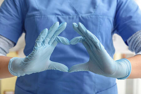 Doctor showing heart shape with hands in clinicの写真素材