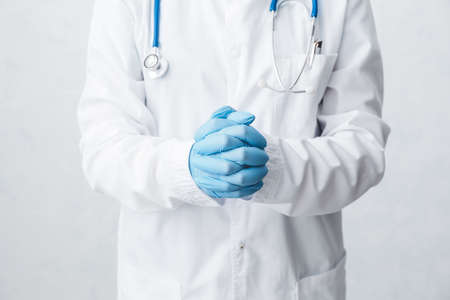 Doctor with medical gloves against light background