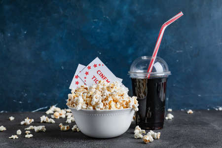 Bowl of tasty popcorn with cinema tickets and cola on dark backgroundの写真素材