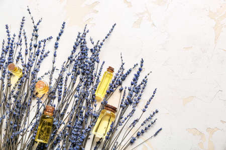 Lavender twigs and bottles with essential oil on light backgroundの写真素材